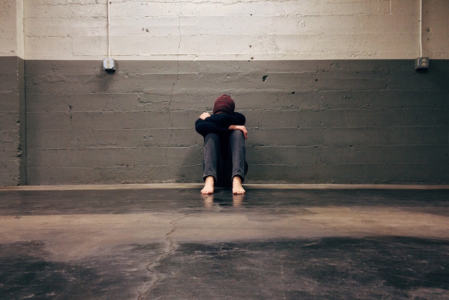 A person sitting on the floor in an empty room.