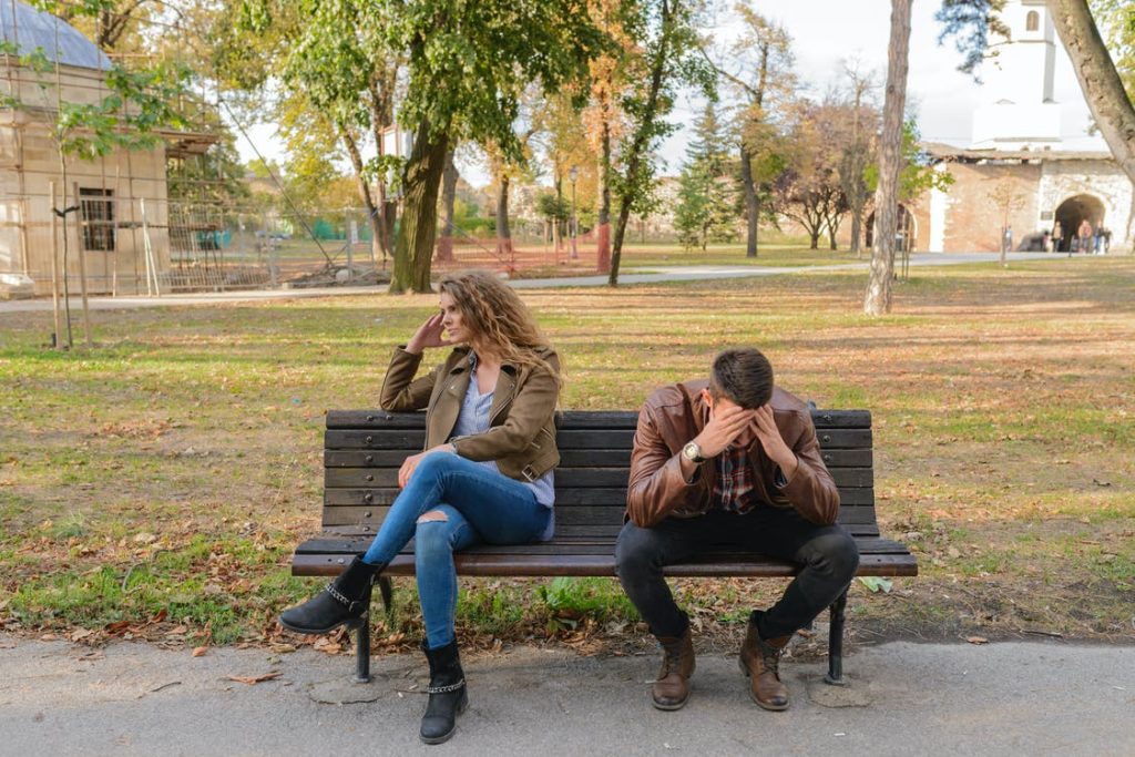 A couple sitting outdoors on a bench during an argument