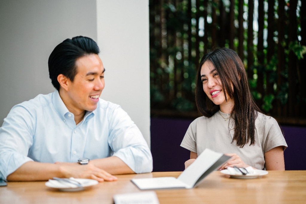 A couple is sitting at a table and communicating with one another.