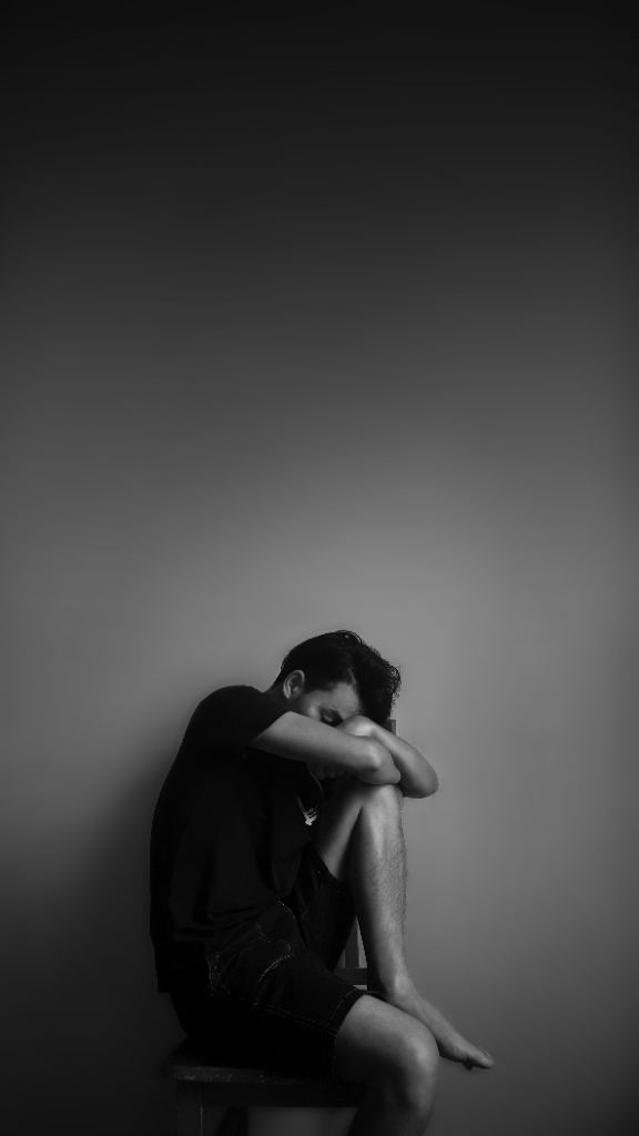 A black and white picture of a sad person sitting down