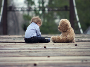 A child sitting with his teddy bear